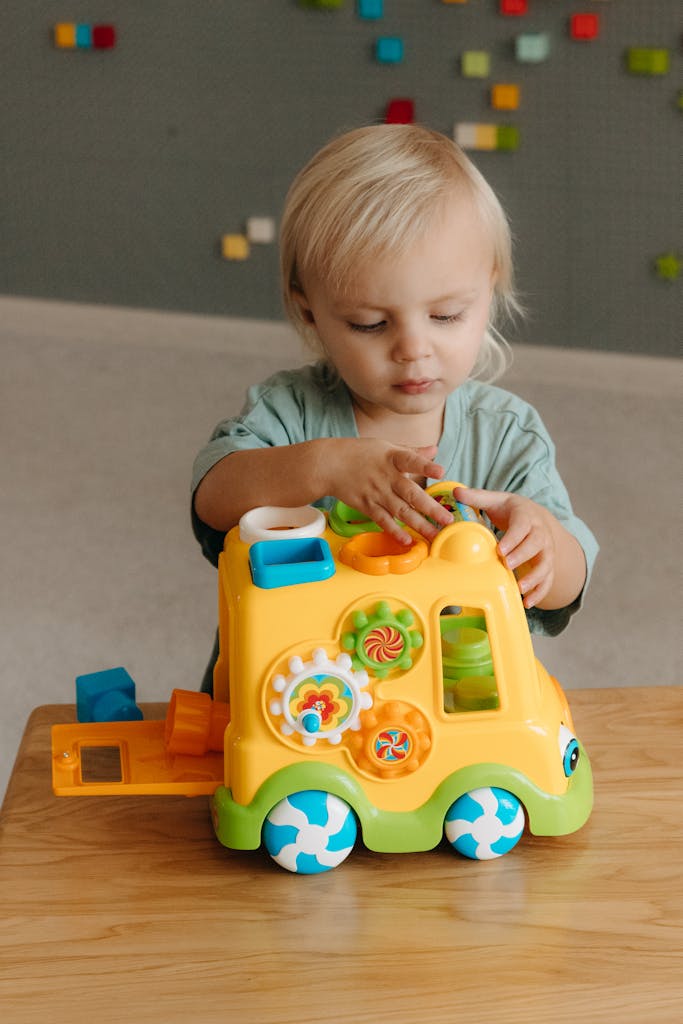 Cute toddler engaging with colorful toy bus inside a playroom.