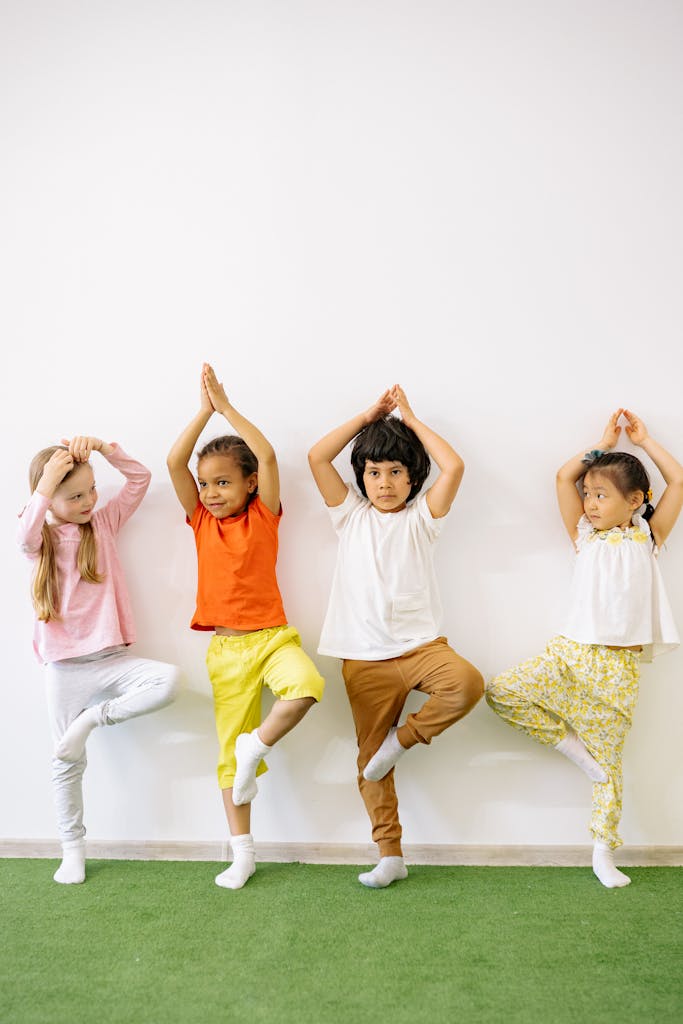 Four diverse children practicing yoga indoors, promoting fun and exercise in a learning environment.