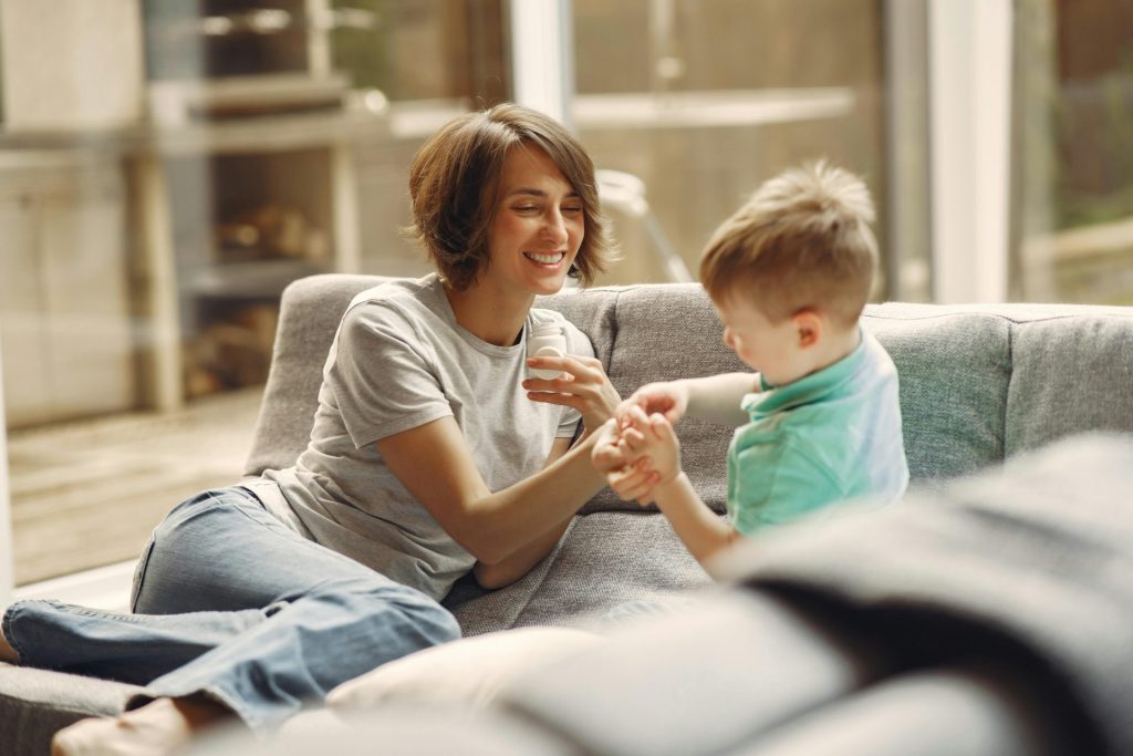 Ein herzerwärmender Moment, in dem Mutter und Sohn gemeinsam lachen und Freude auf dem Sofa im Haus teilen.