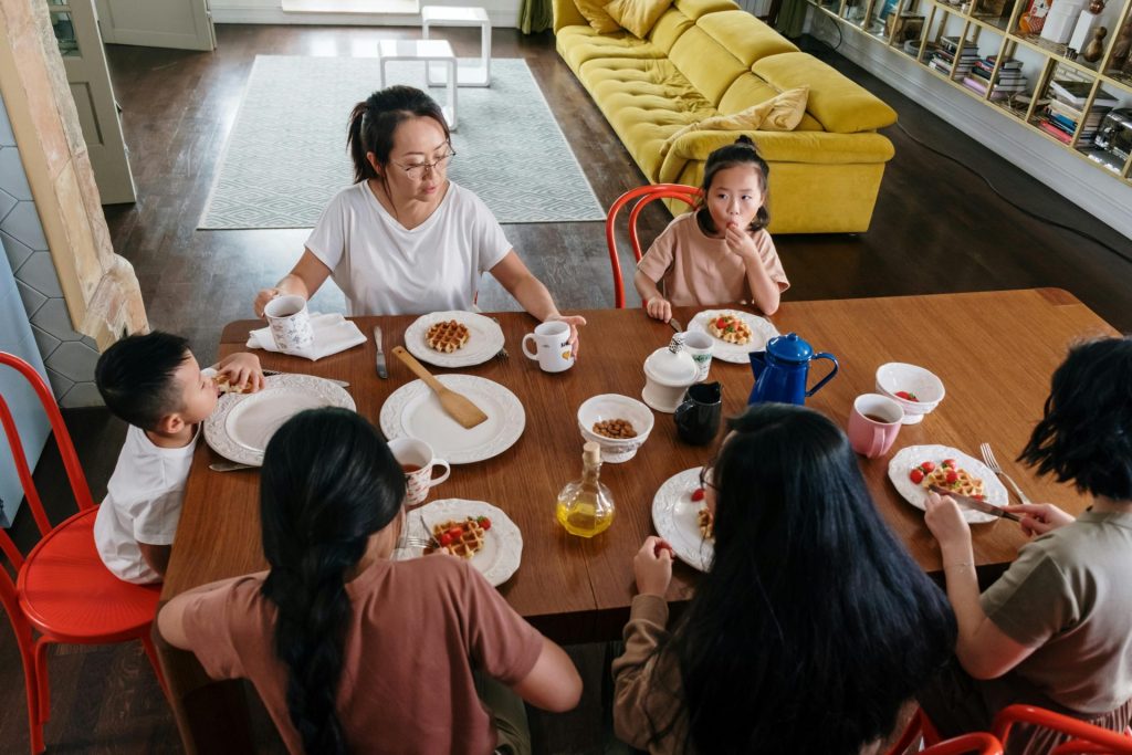 Eine asiatische Familie genießt gemeinsam das Frühstück in einem gemütlichen Zuhause und stärkt so das Zusammengehörigkeitsgefühl und die Bindung.