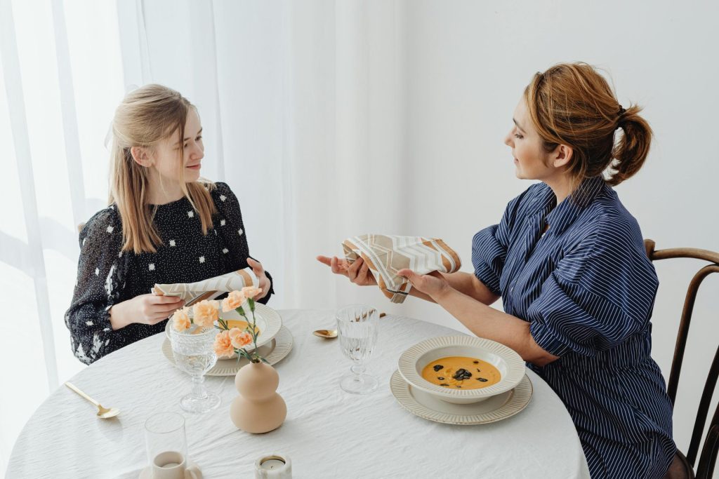 Eine Mutter und ihre Tochter essen gemeinsam, wobei sie Wert auf Tischmanieren legen und beim Mittagessen ihre Bindung stärken.