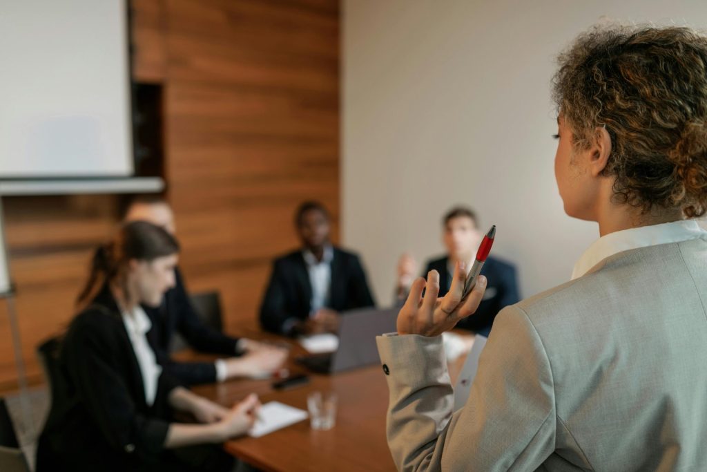 Ein professionelles Team führt eine Geschäftsbesprechung durch, wobei der Fokus auf dem Präsentator mit einem Stift liegt.
