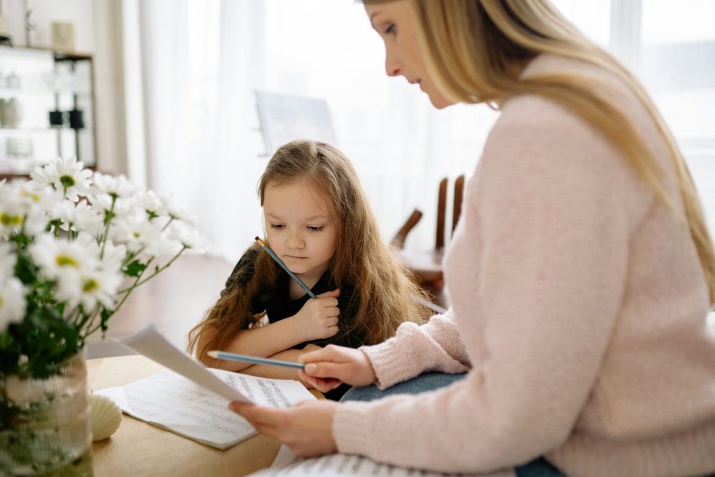 Eine Mutter und ihre Tochter lernen gemeinsam zu Hause Klavier, fördern so die musikalische Bildung und die Bindung.